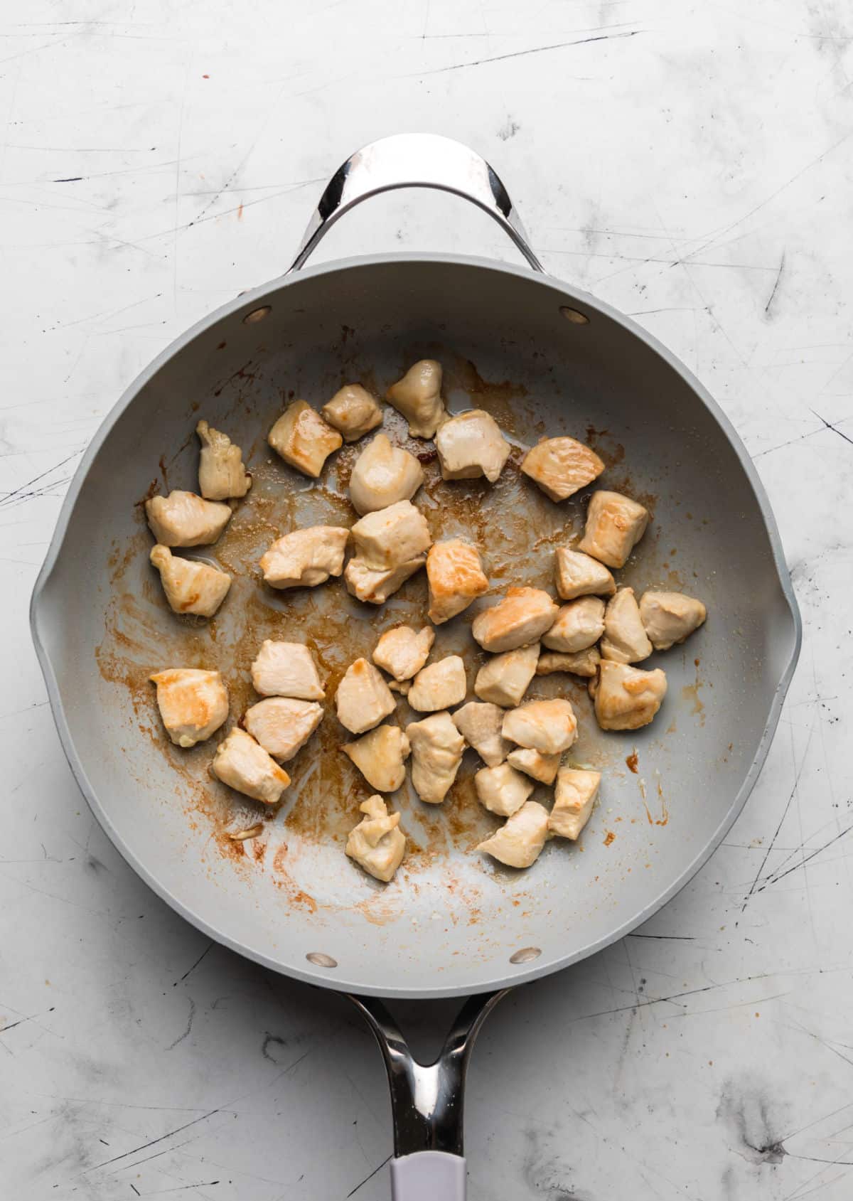 Cooked chicken pieces in a gray skillet. 