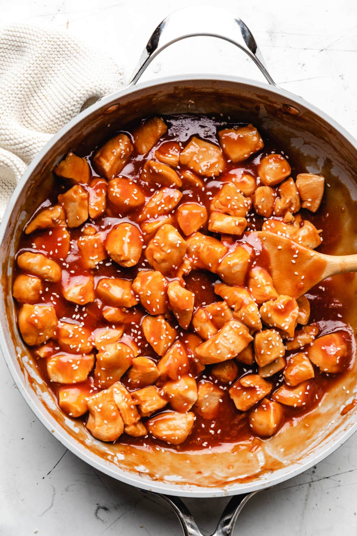 A skillet of orange chicken topped with sesame seeds. 