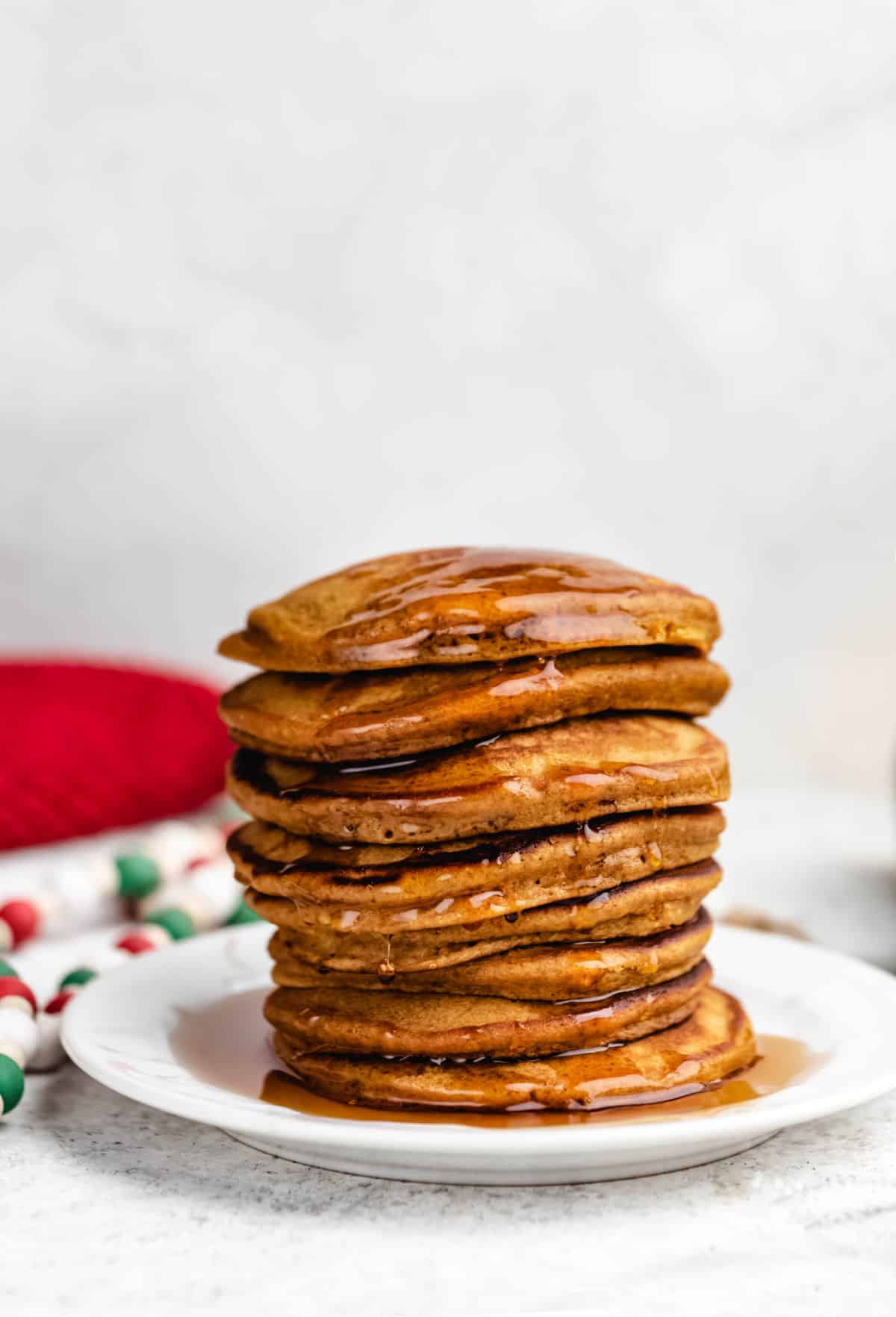 A stack of gingerbread pancakes next to a red knit napkin. 