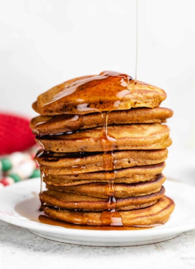 Maple syrup pouring onto a stack of gingerbread pancakes.