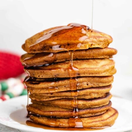 Maple syrup pouring onto a stack of gingerbread pancakes.