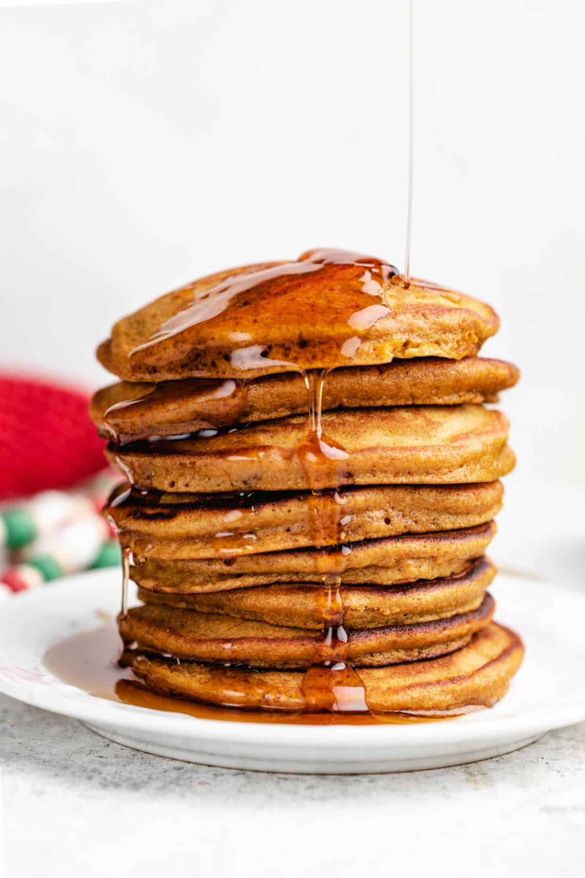 Maple syrup pouring onto a stack of gingerbread pancakes.