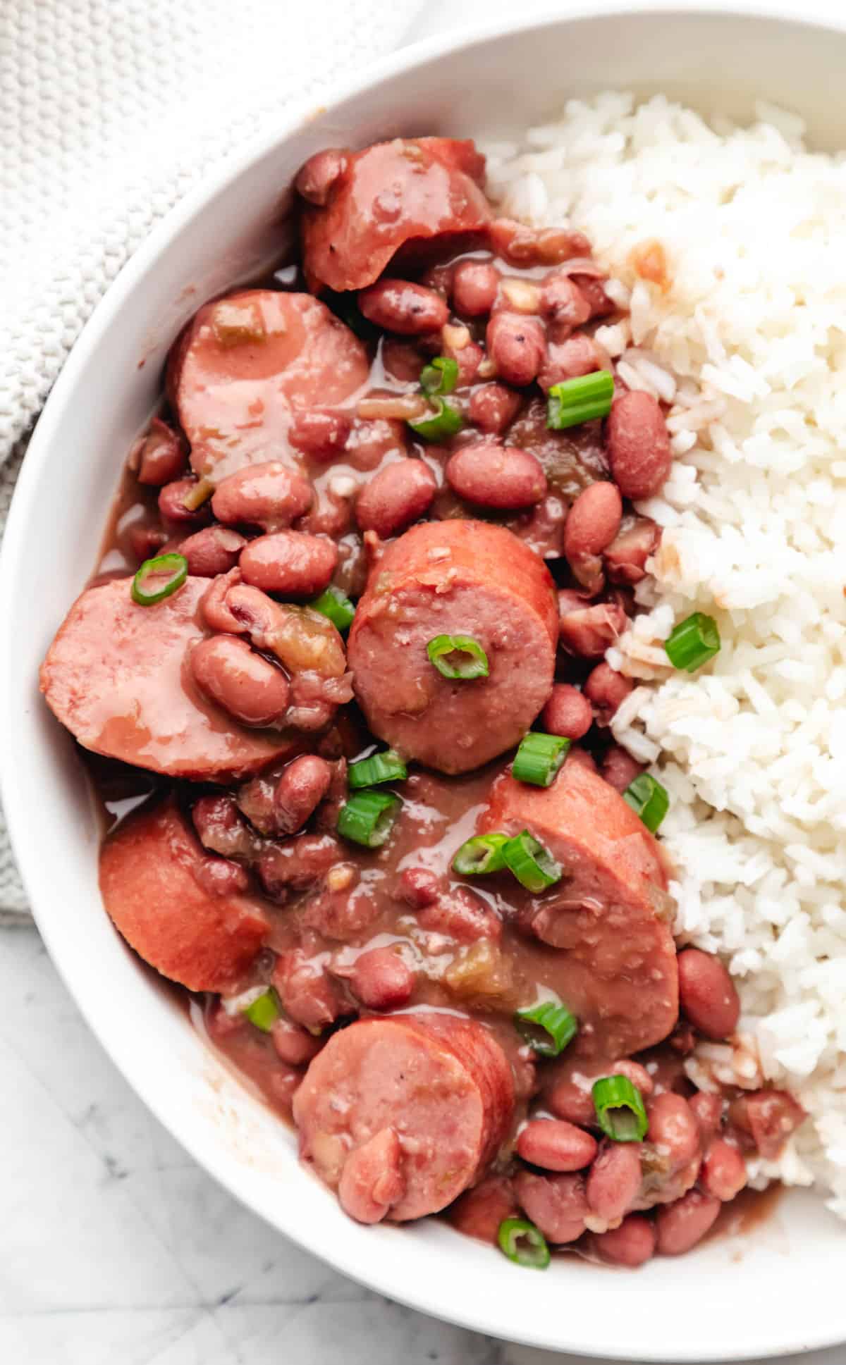 Slow cooker red beans and rice in a bowl topped with sliced green onion.