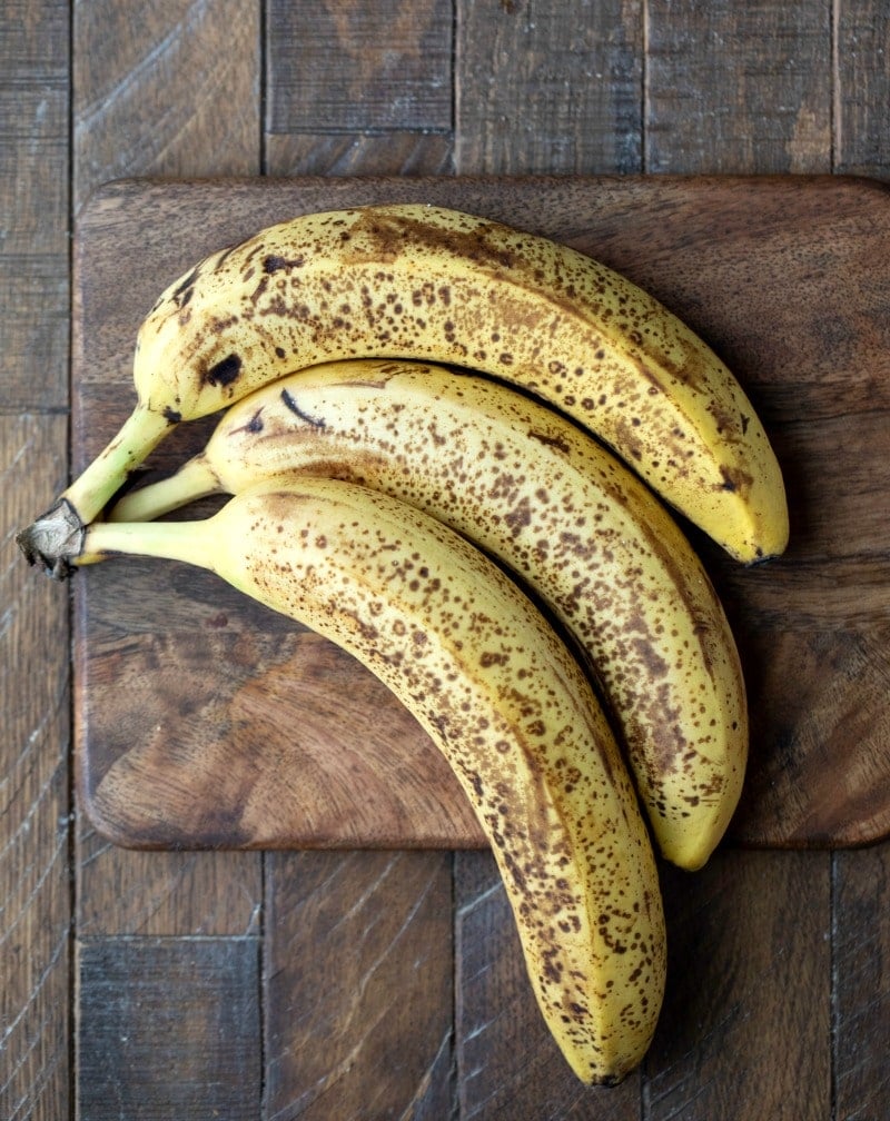 Speckled bananas on a wooden cutting board