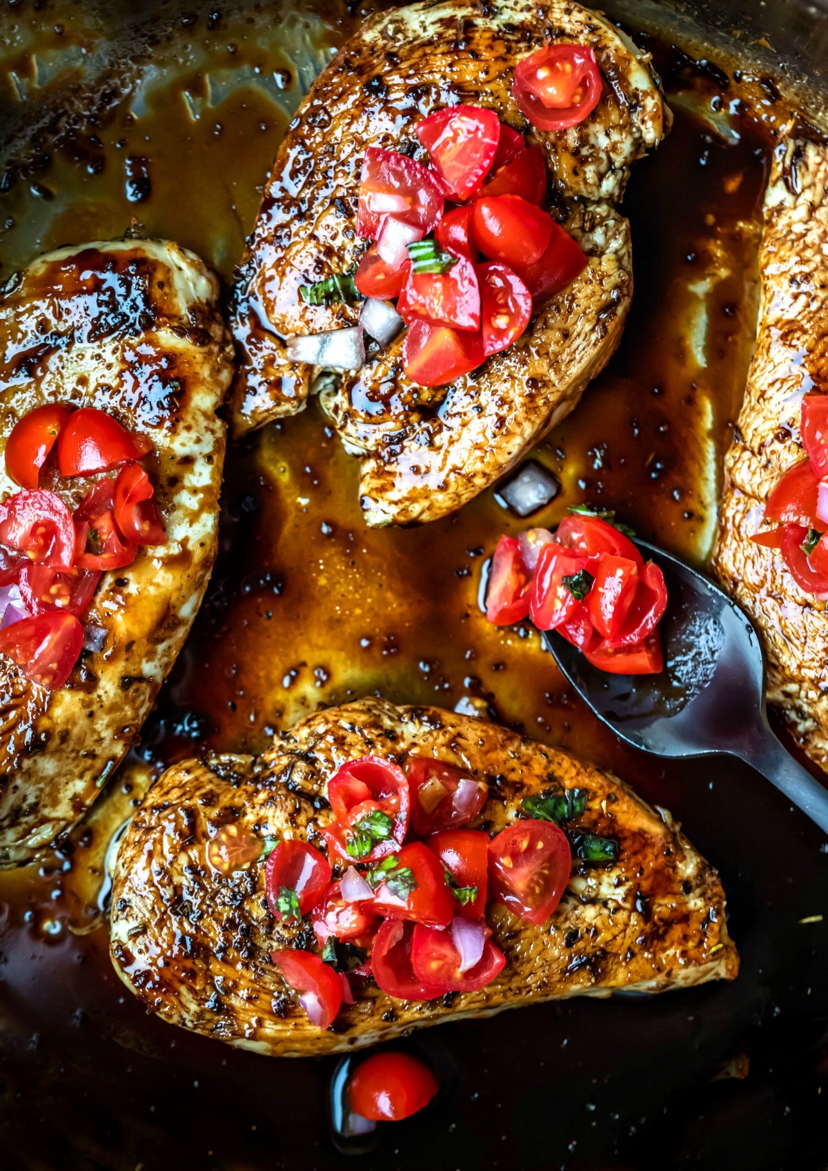 4 pieces of bruschetta chicken in a silver skillet