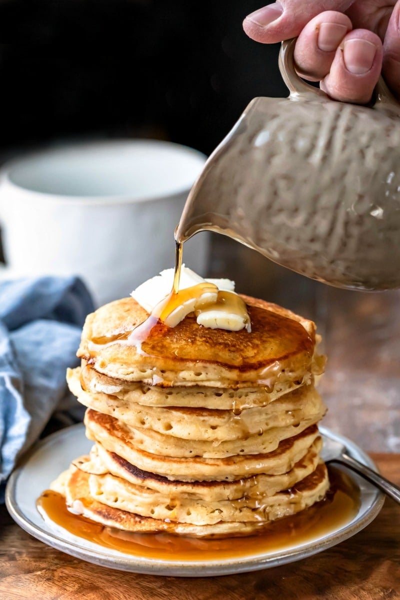 Syrup pouring onto a stack of multigrain pancakes