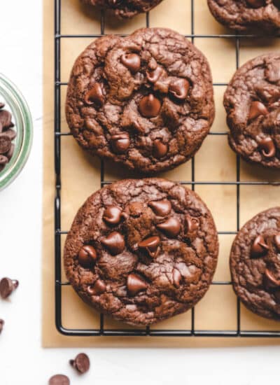 Chocolate chocolate chip cookies next to a dish of chocolate chips.