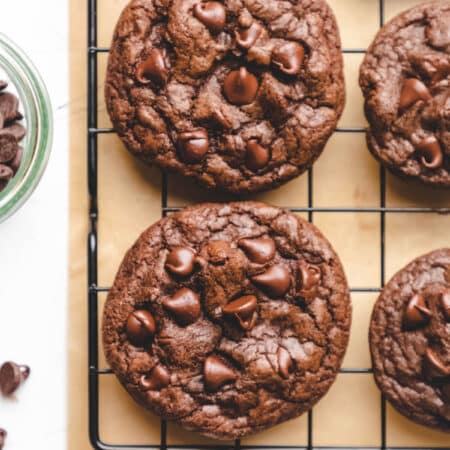 Chocolate chocolate chip cookies next to a dish of chocolate chips.