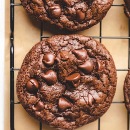 Two easy chocolate chocolate chip cookies on a cooling rack.