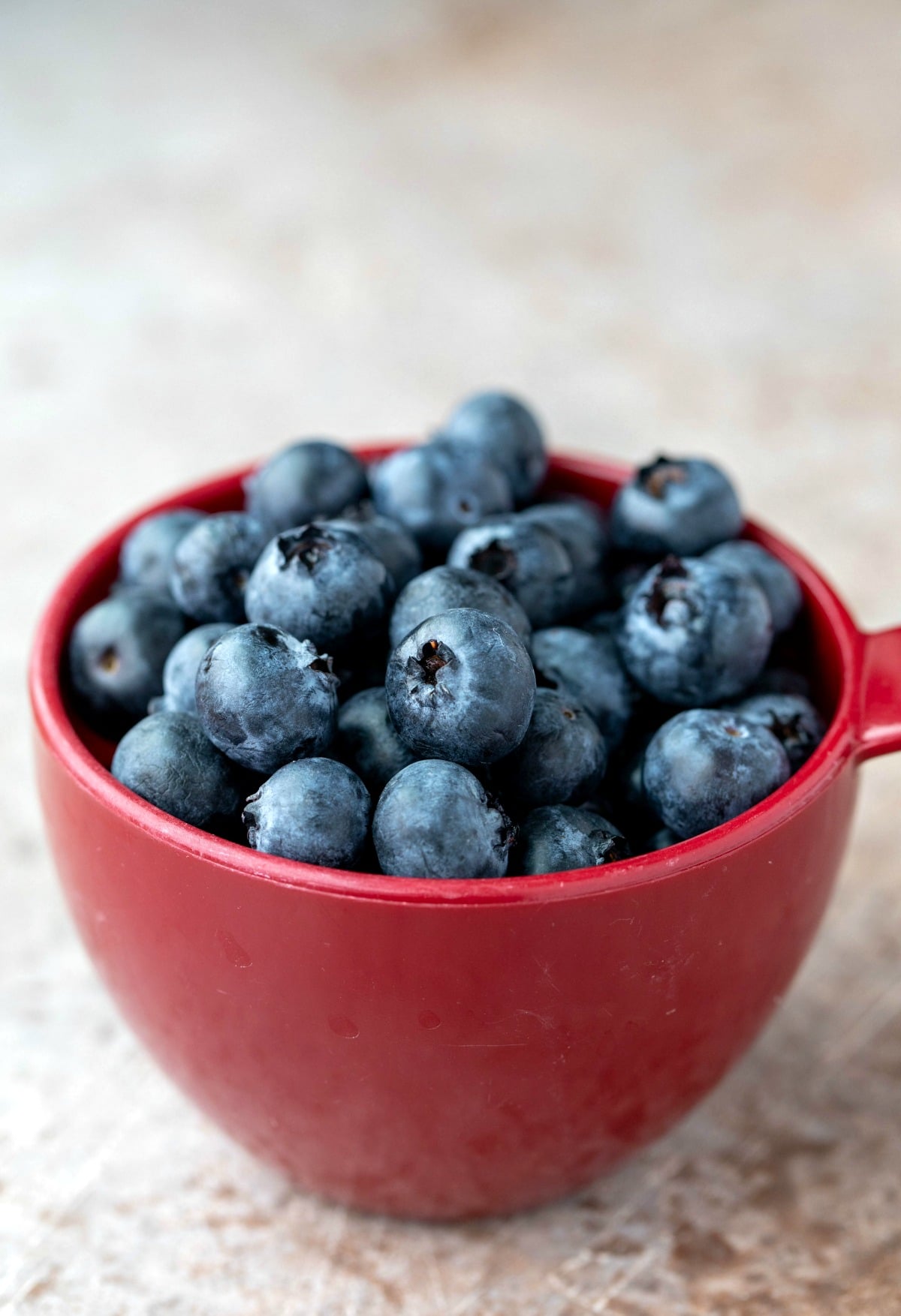 Red measuring cup with fresh blueberries in it