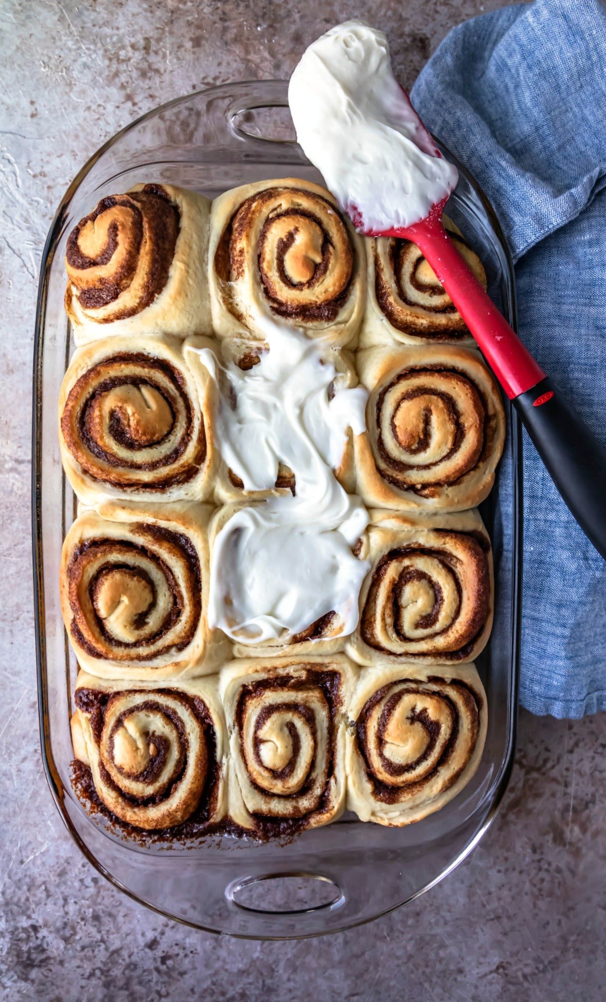 Cream cheese frosting spreading on homemade cinnamon rolls