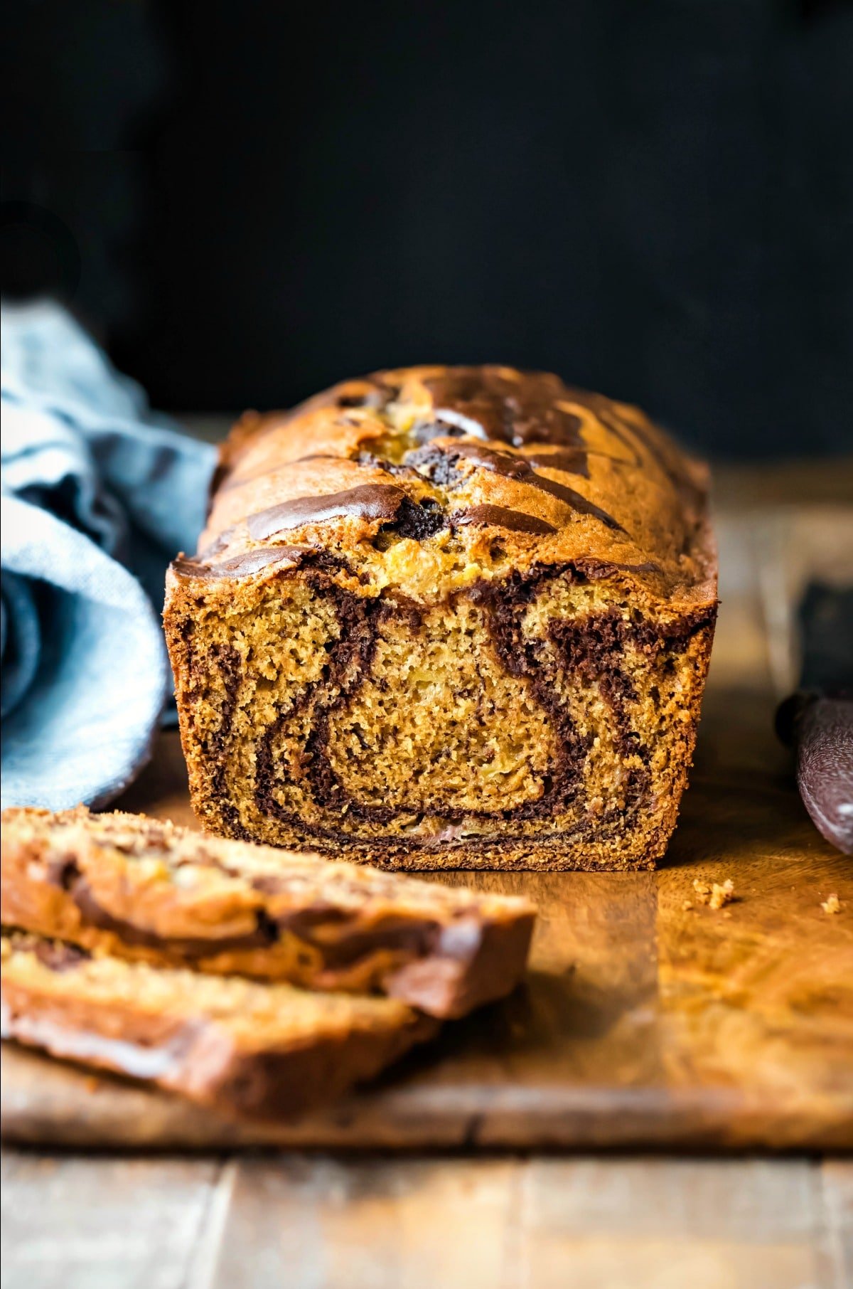 Loaf of marbled banana bread next to a blue linen napkin