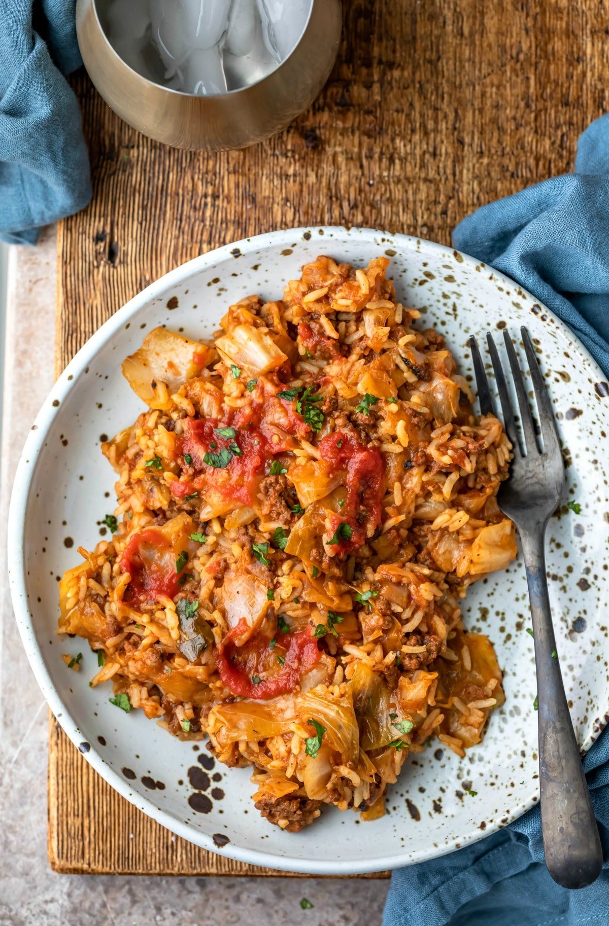 Plate with cabbage roll bowl on it next to a blue linen napkin