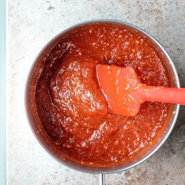 Uncooked pizza sauce in a silver saucepan