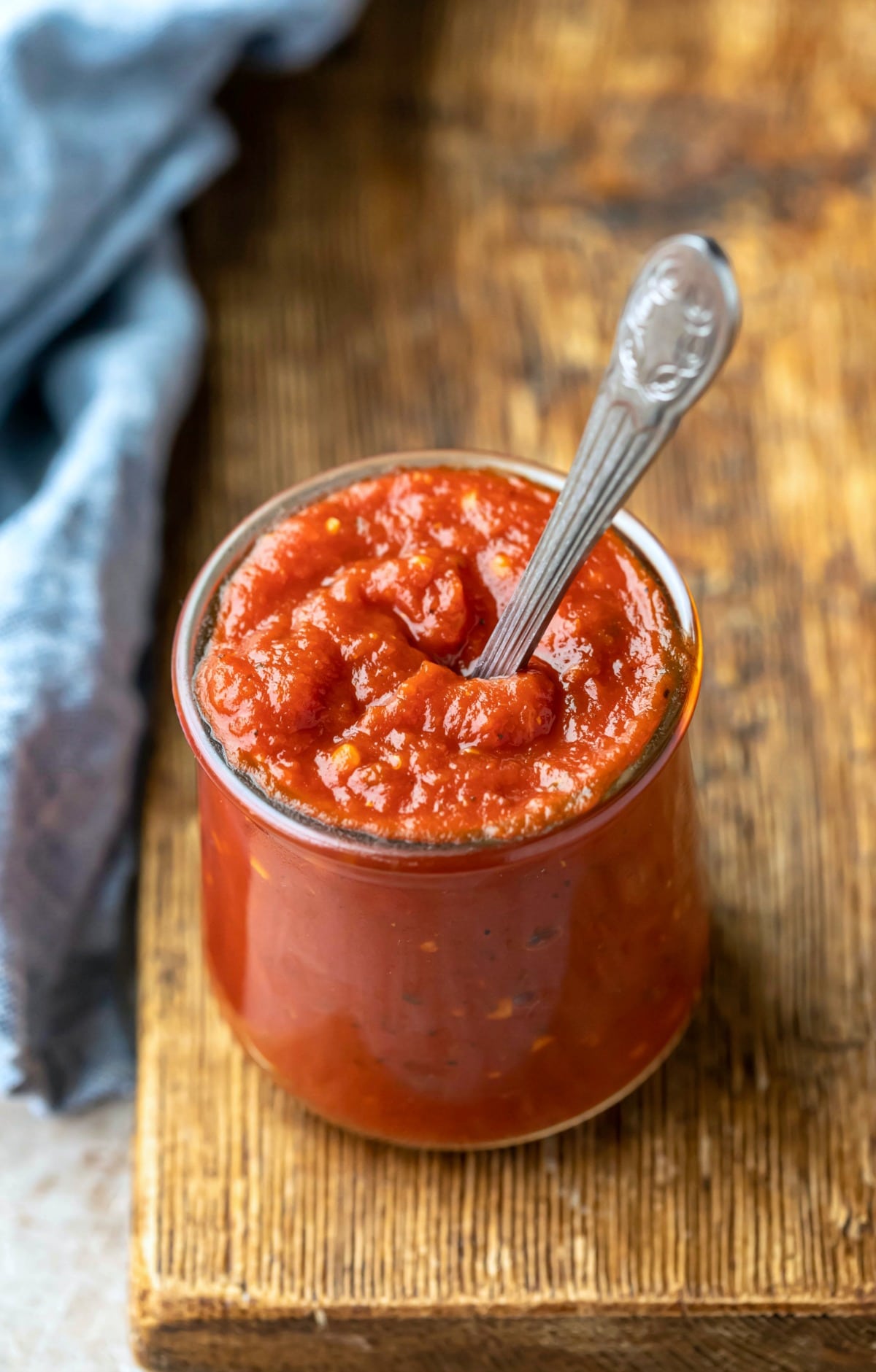 Glass jar of pizza sauce with a silver spoon in it