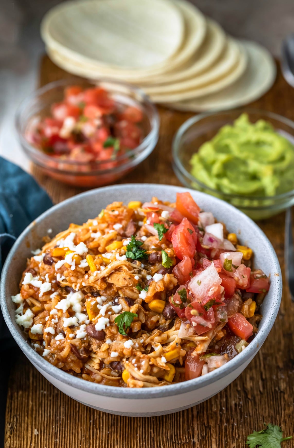 Instant Pot Burrito Bowl Recipe Burrito bowl next to a dish of guacamole and pico de gallo