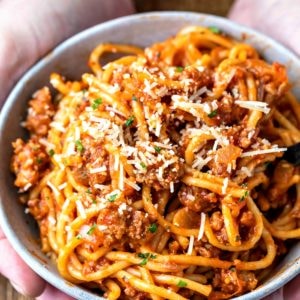 Hands holding a bowl of spaghetti