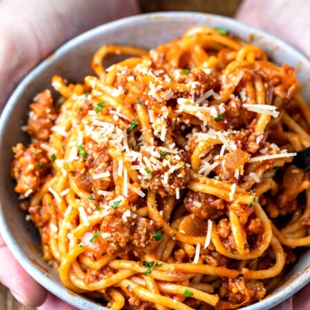 Hands holding a bowl of spaghetti