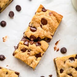 Chocolate chip cookie bars surrounded by scattered chocolate chips.