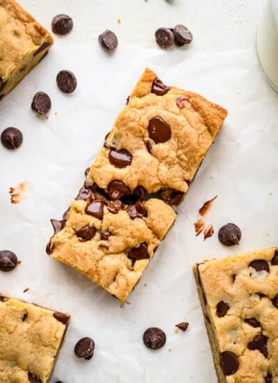 Chocolate chip cookie bars surrounded by scattered chocolate chips.