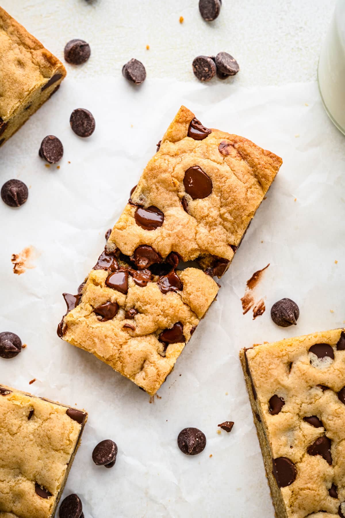 Chocolate chip cookie bars surrounded by scattered chocolate chips.