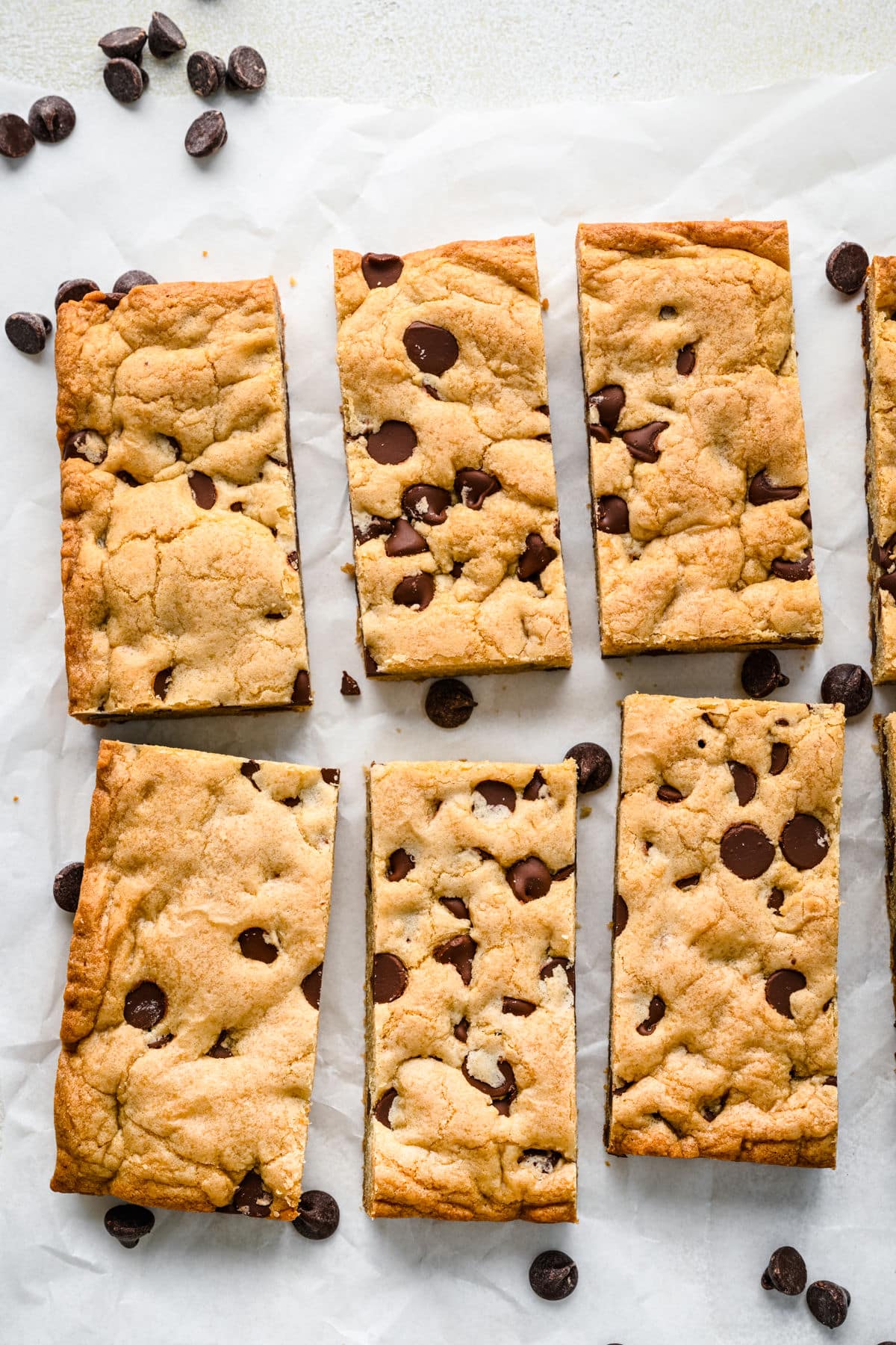 Chocolate chip cookie bars in rows on a piece of parchment paper. 
