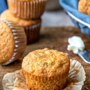 Unwrapped carrot cake muffin next to a butter knife with butter