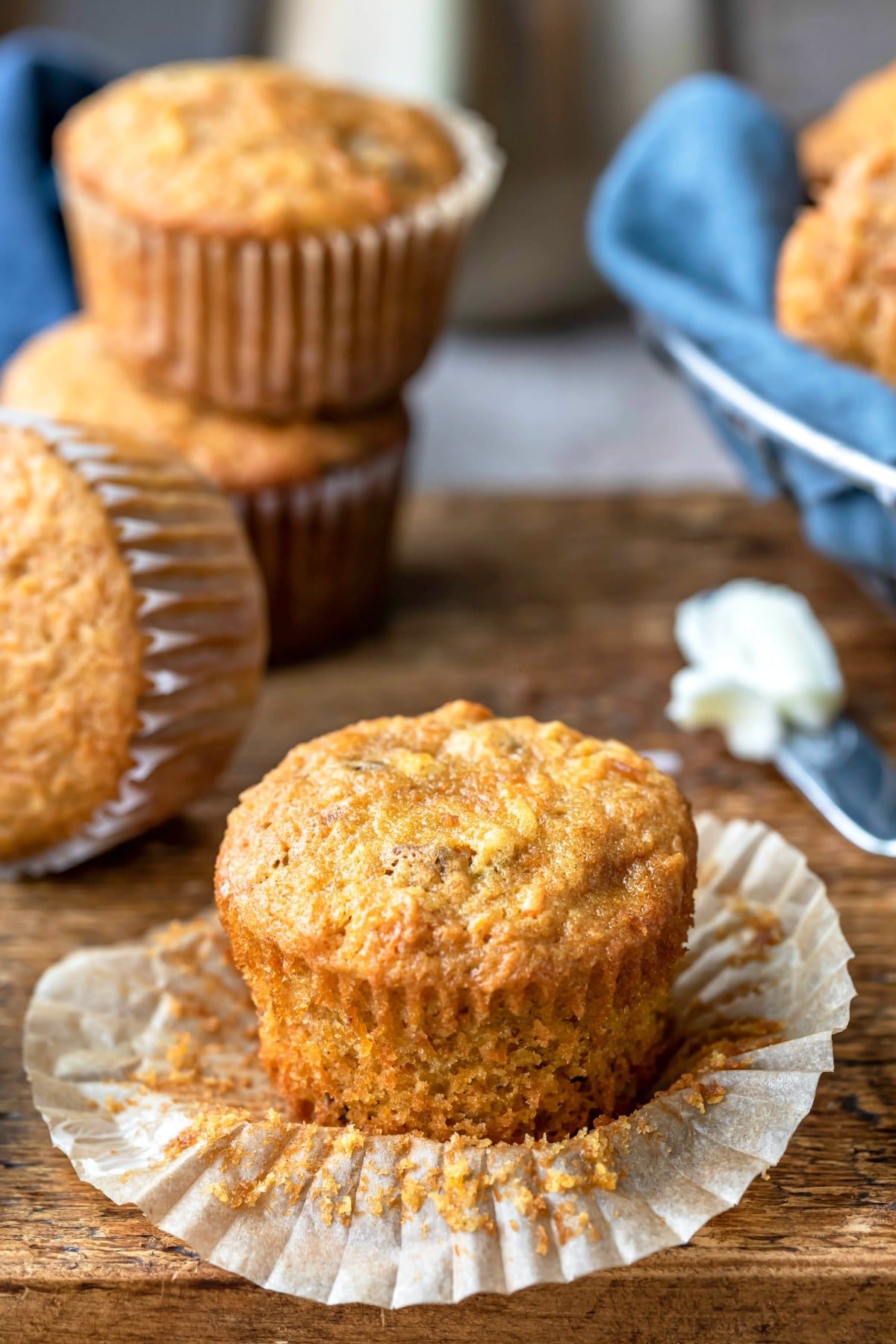 Unwrapped carrot cake muffin next to a butter knife with butter