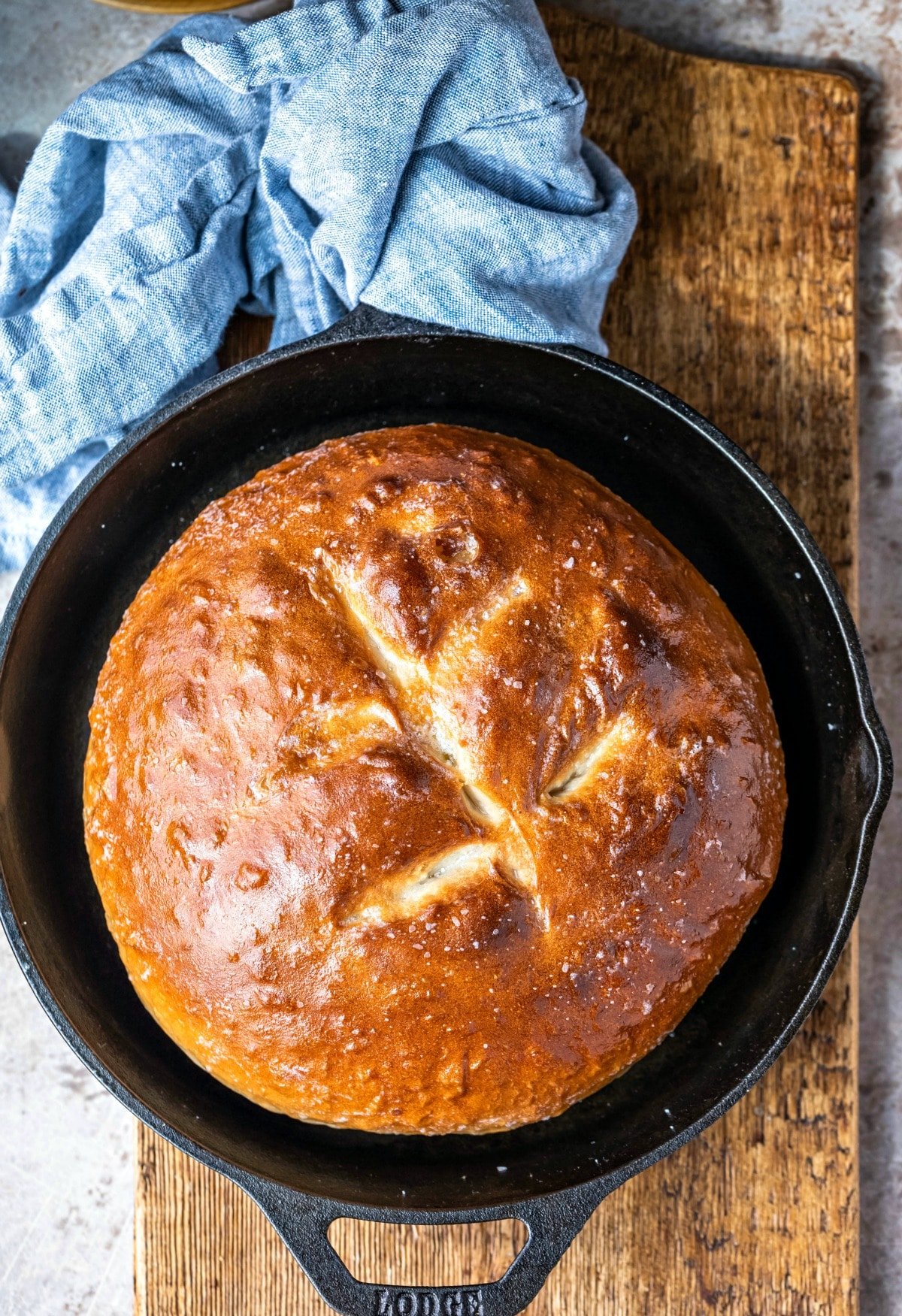 Cast iron skillet with a loaf of baked bread on a wooden cutting board