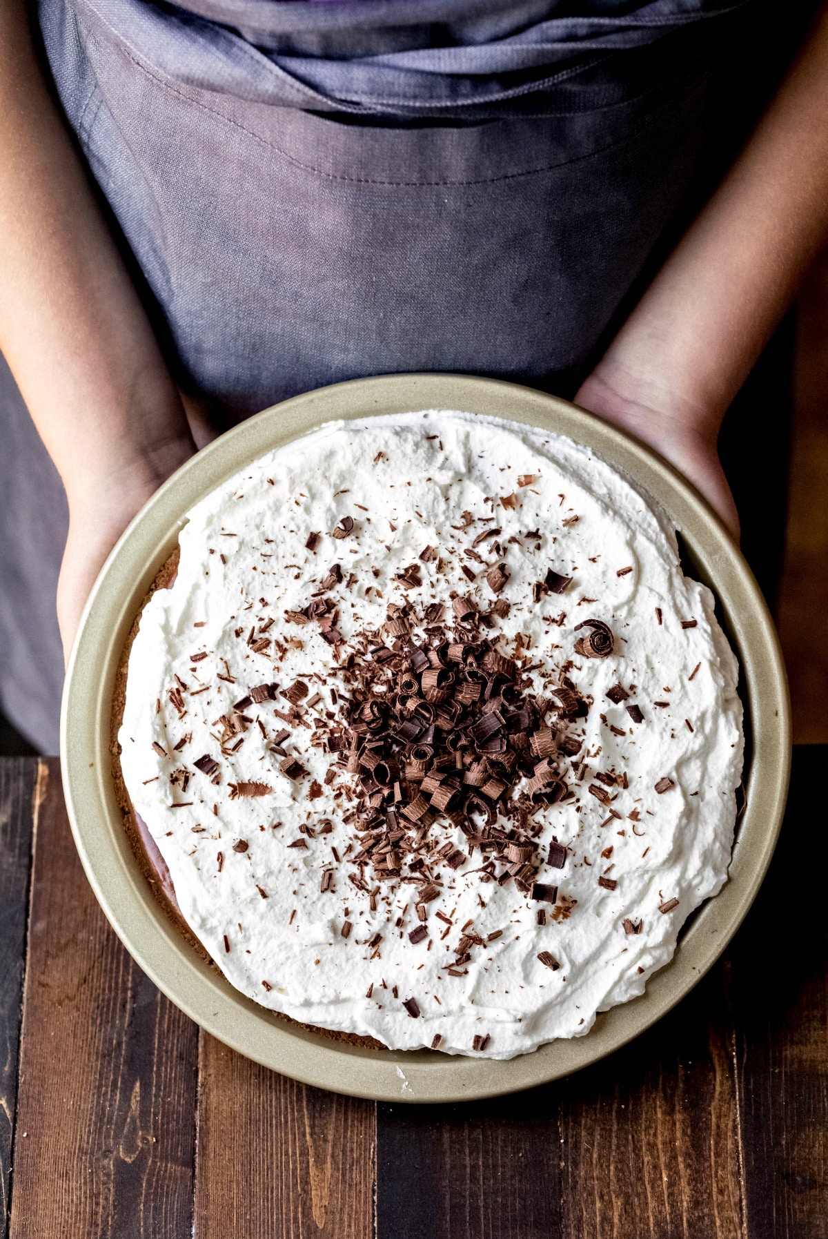 Two hands holding a no bake chocolate pie in a pan