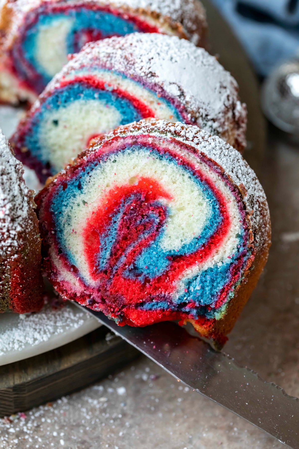 Knife cutting a slice of red, white, and blue marble cake