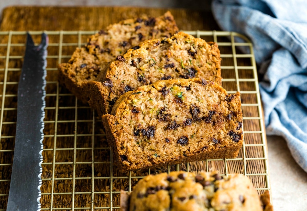 Slices of chocolate chip zucchini bread next to a bread knife