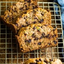 Three slices of chocolate chip zucchini bread on a gold wire cooling rack