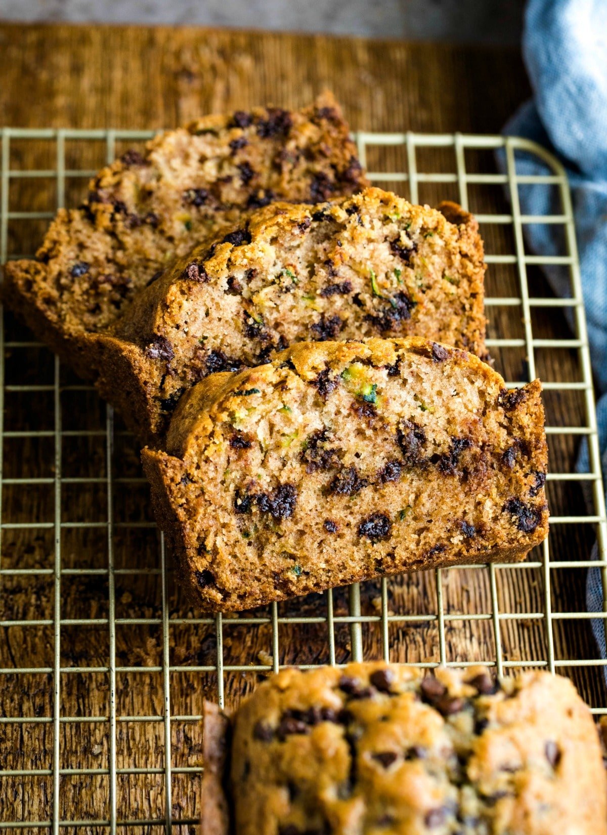 Three slices of chocolate chip zucchini bread on a gold wire cooling rack