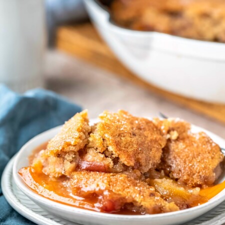 Dish of brown sugar peach cobbler next to a blue linen napkin