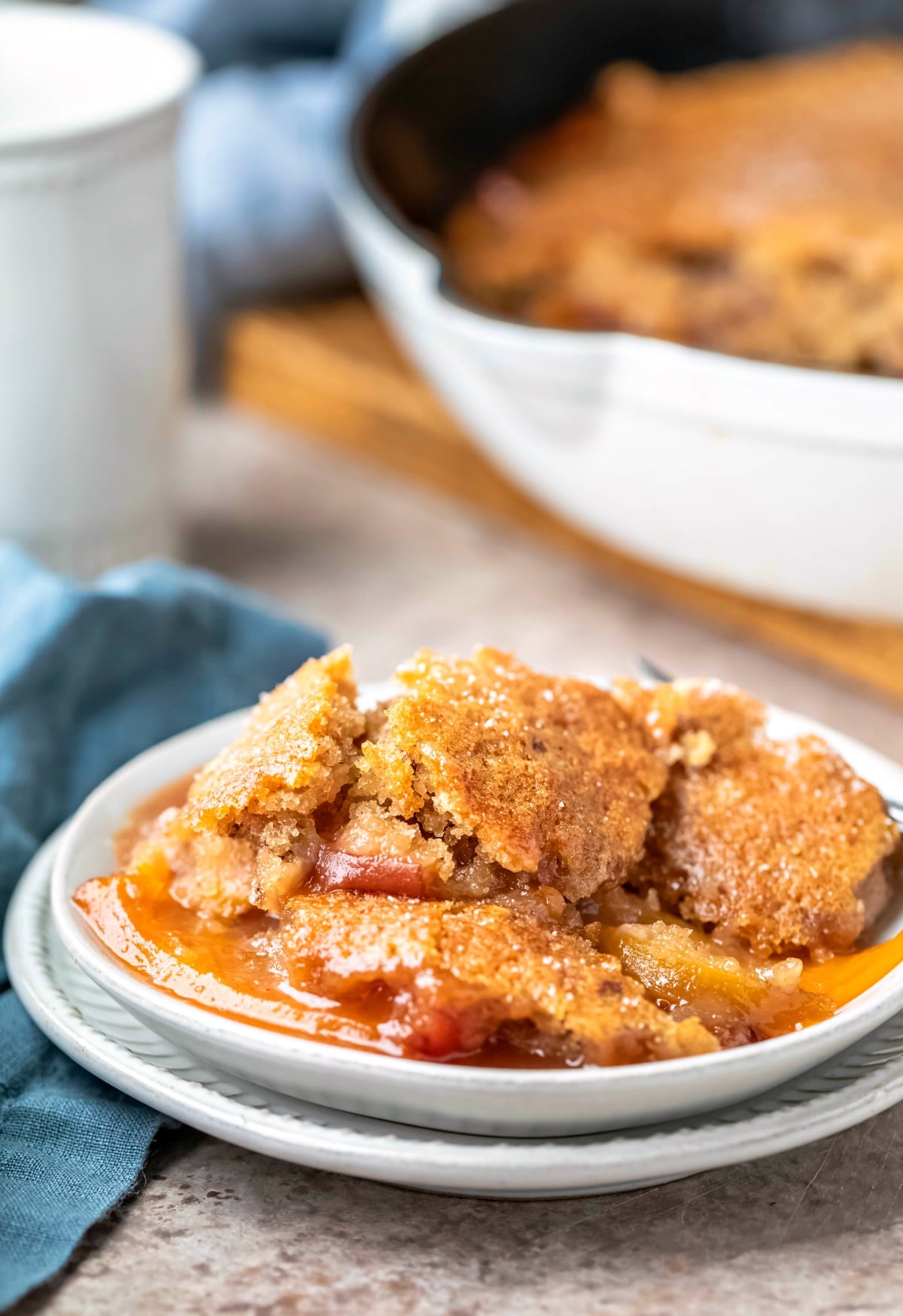 Dish of brown sugar peach cobbler next to a blue linen napkin