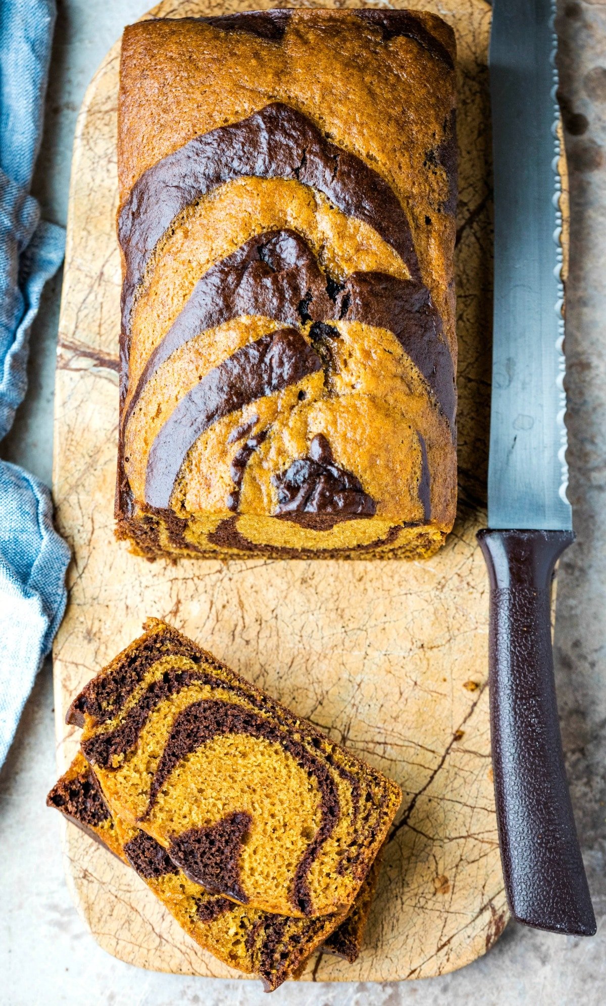 Two slices of chocolate marble pumpkin bread on a marble cutting board