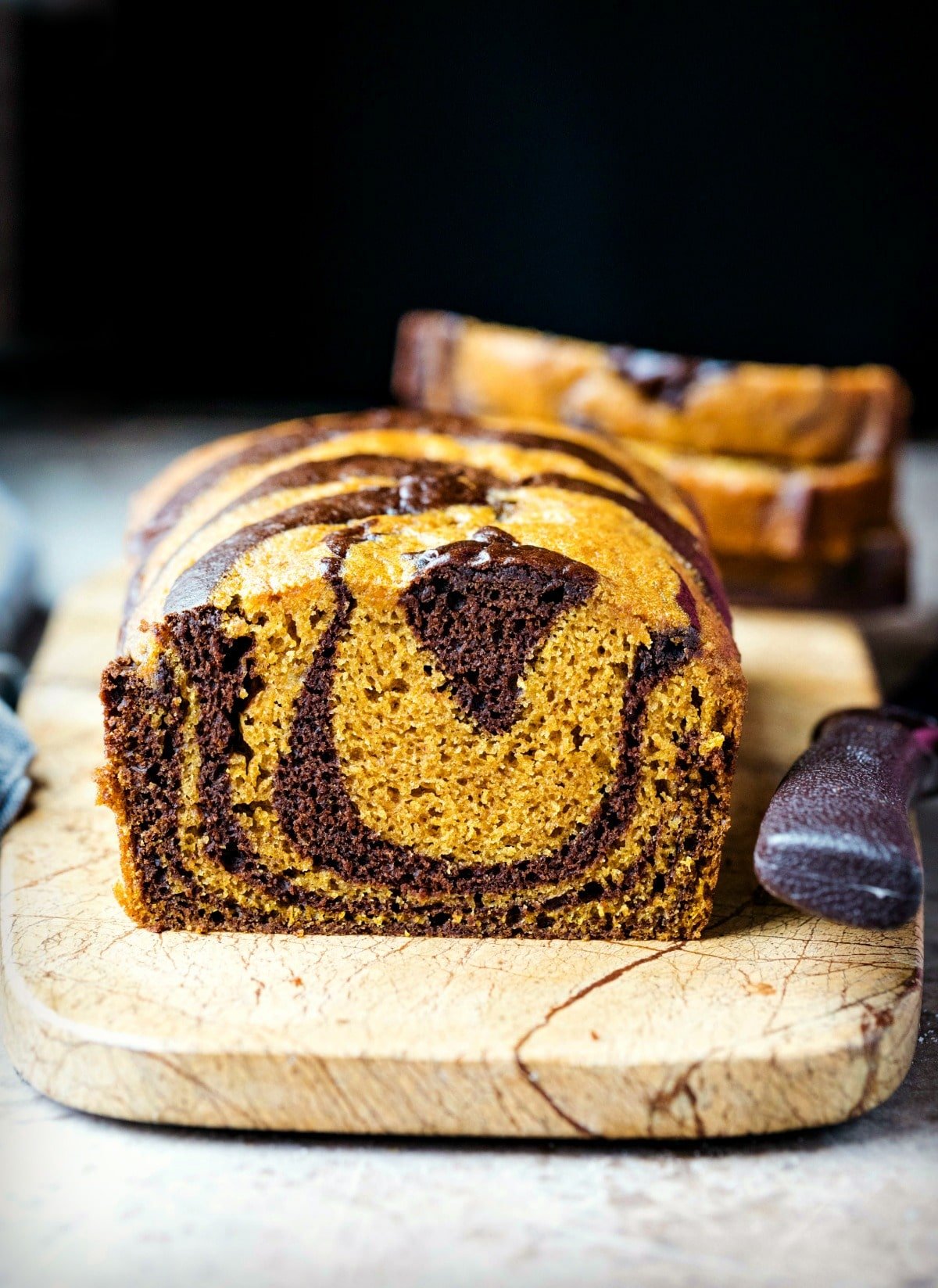 Loaf of chocolate marble pumpkin bread on a marble cutting board
