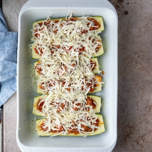 Uncooked zucchini boats in a white baking pan