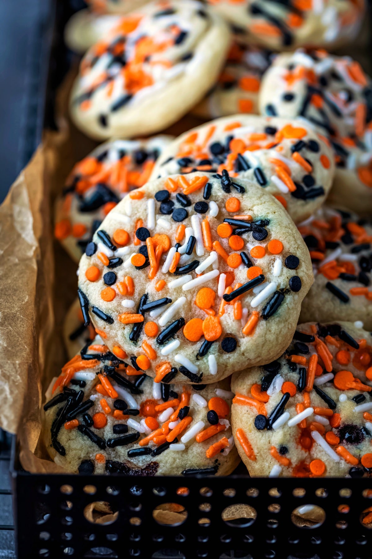 Stack of Halloween sprinkle cookies in a black metal container. 