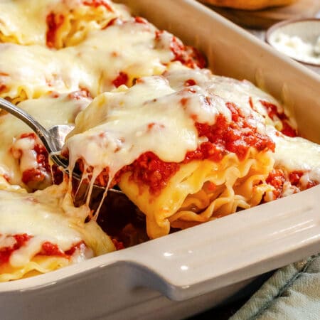 A server lifting a lasagna roll from the pan.