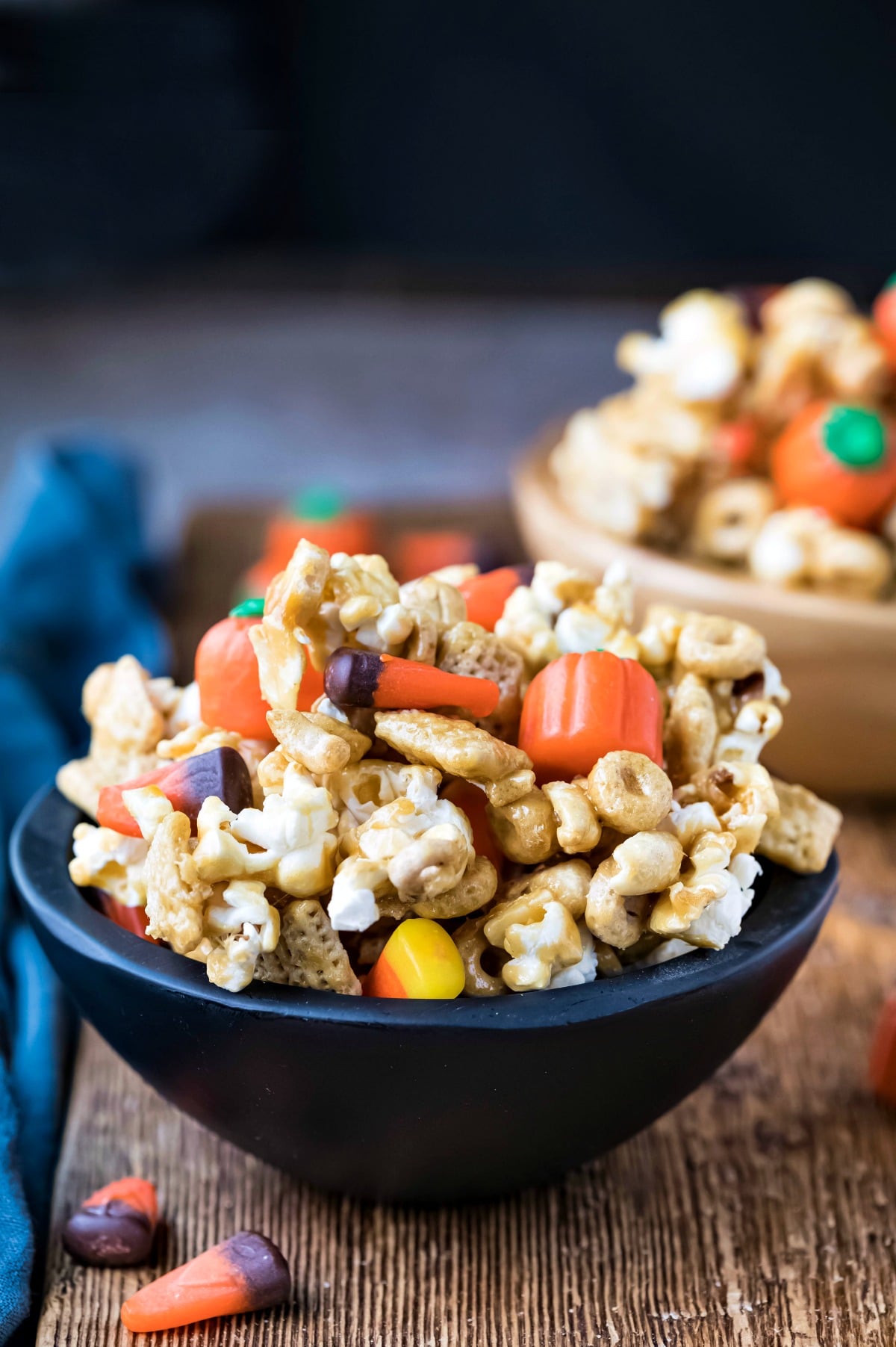 Halloween snack mix in a black wooden bowl on a wooden cutting board