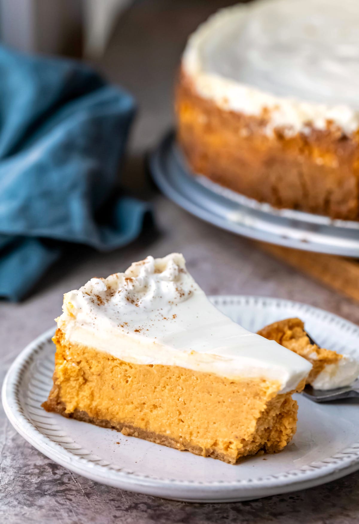 Slice of pumpkin cheesecake on a white plate with a bite missing