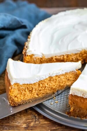 Knife cutting a slice of pumpkin cheesecake.