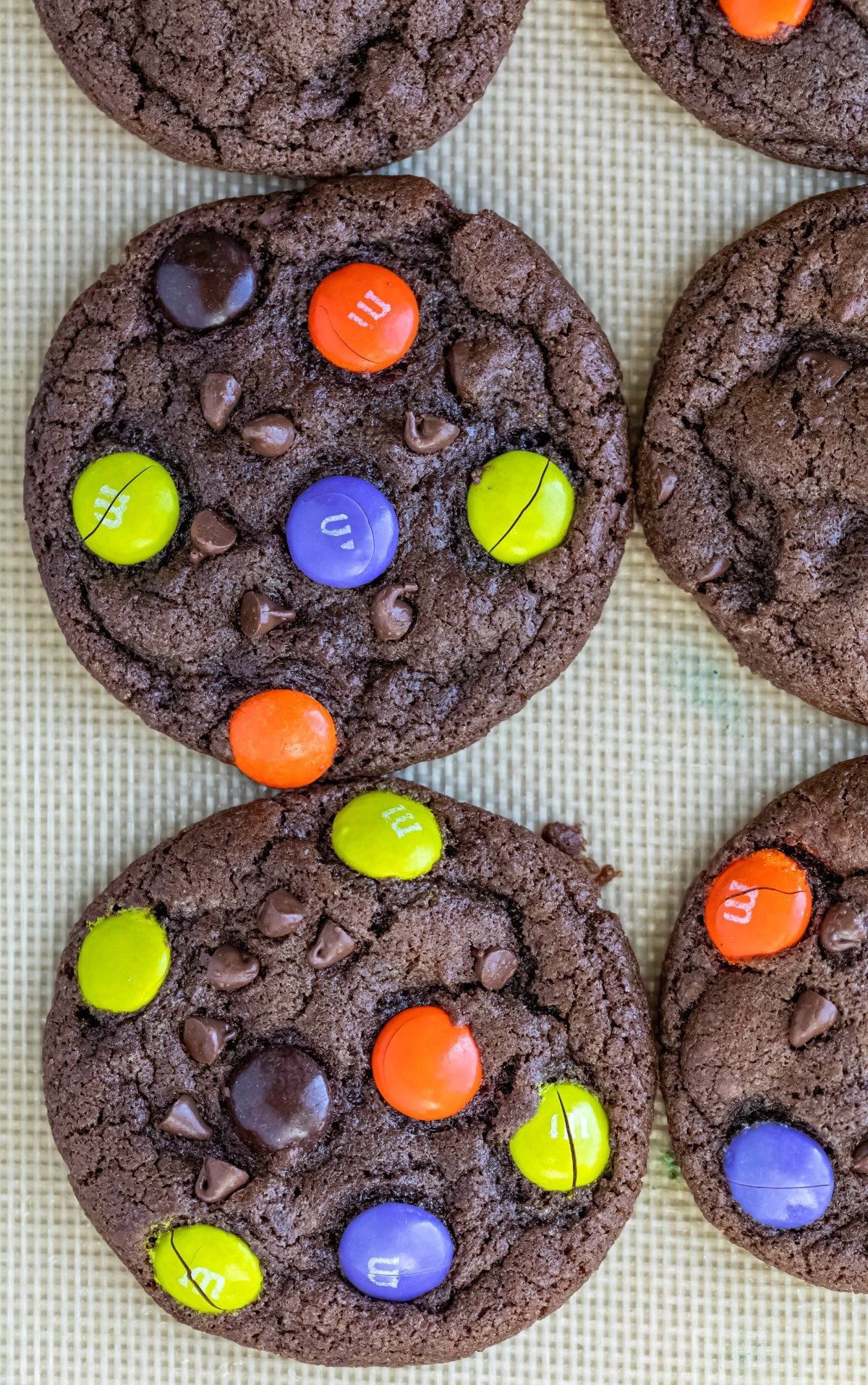 Halloween chocolate M&M cookies on a silicone baking mat.