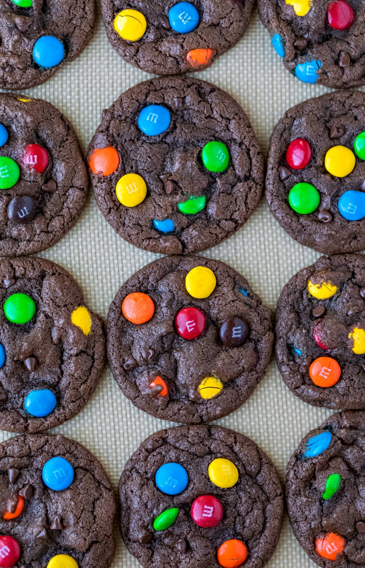 Chocolate M&M cookies on a silicone baking mat