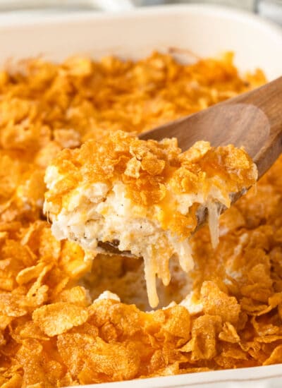 A wooden spoon holding a scoop of funeral potatoes.