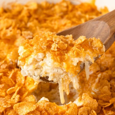 A wooden spoon holding a scoop of funeral potatoes.