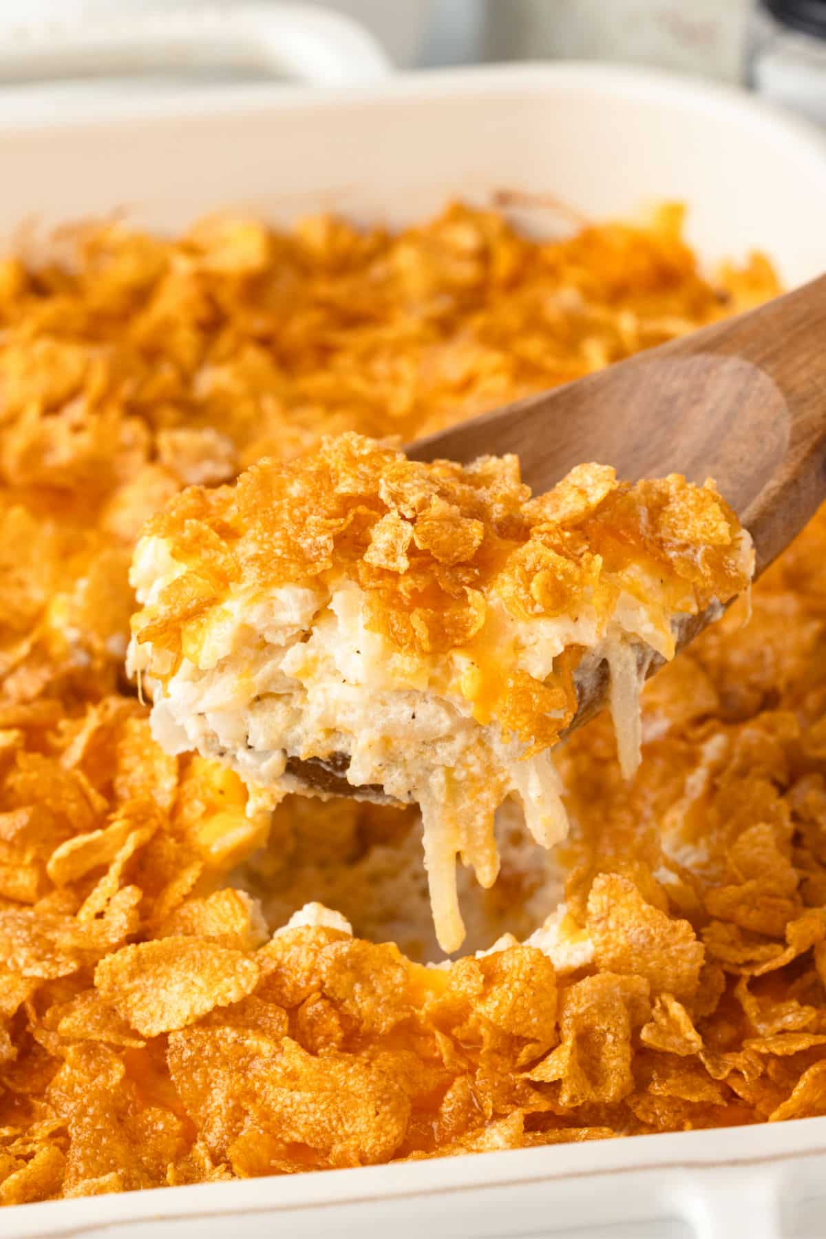 A wooden spoon holding a scoop of funeral potatoes.