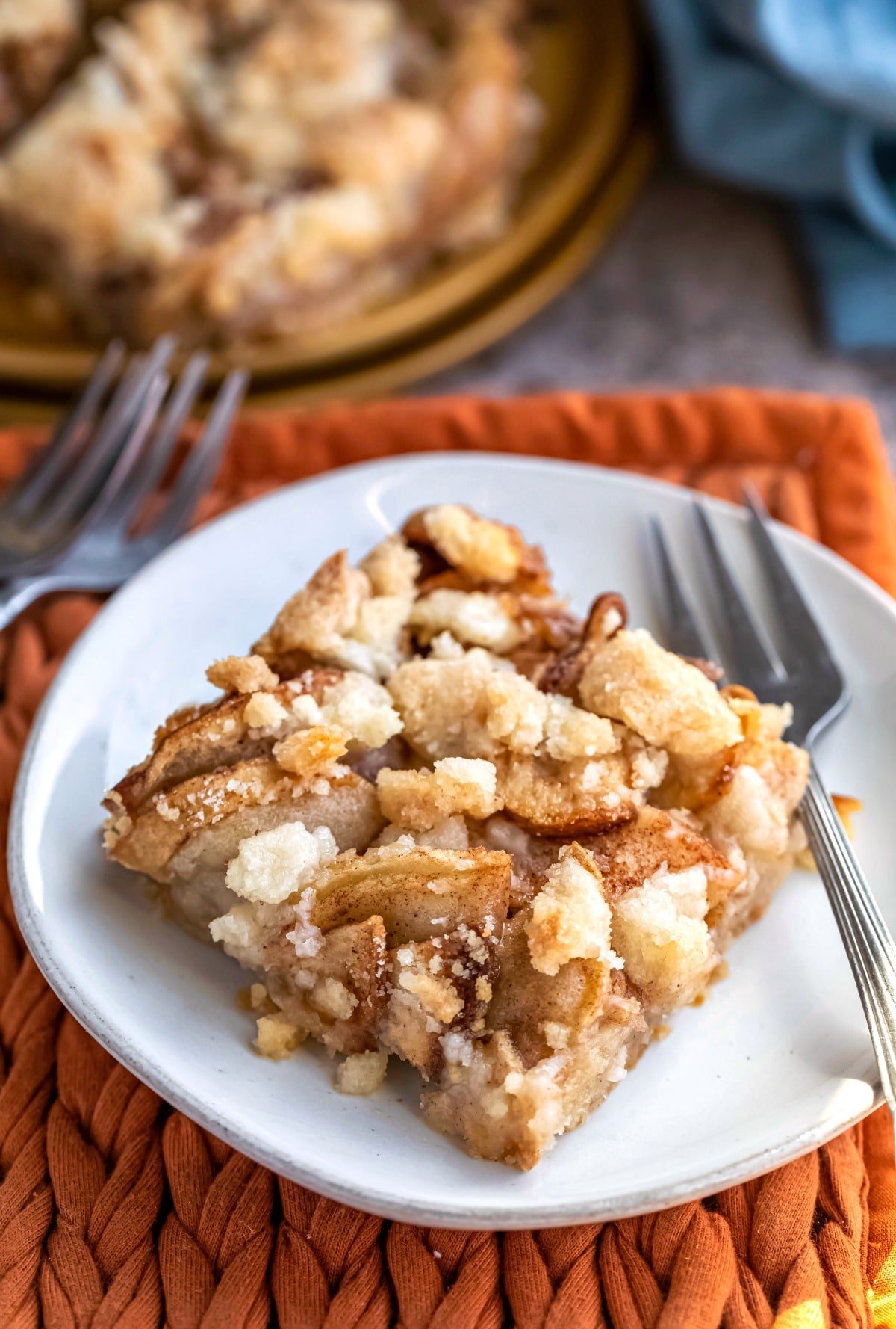 Plate with apple crumb bar on it on an orange cloth